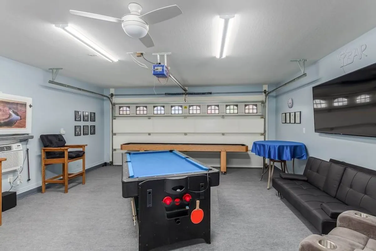 An interior view of a playful and social space, complete with a pool table, a cozy sofa, a vibrant blue table, and colorful wall art. The area is designed for both playing games and relaxing, echoing a communal, family-friendly vibe.