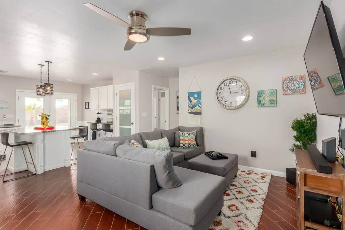 A welcoming family room with a large gray sectional sofa, decorative pillows, a TV, and wall art. The setting is cozy and ideal for gatherings, conversations, or relaxing after a day of fun.